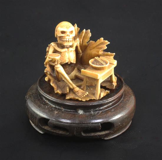 A Japanese ivory netsuke of a skeleton, early 20th century, signed Sei..? 3.3cm, wood stand